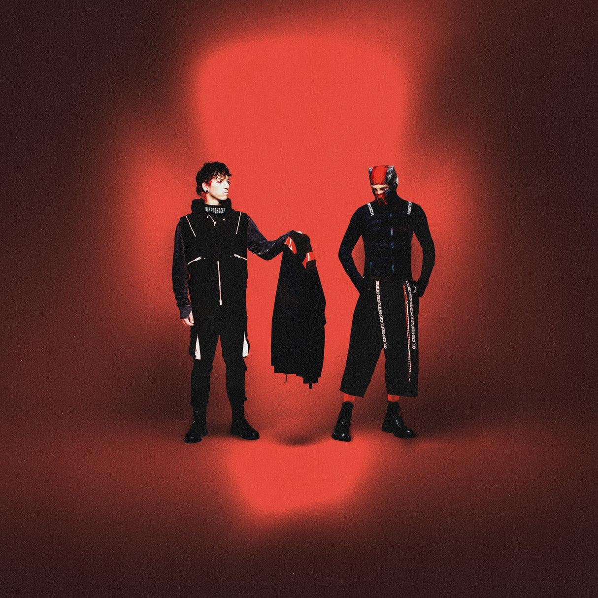 Two people in black outfits with a red light on a dark background