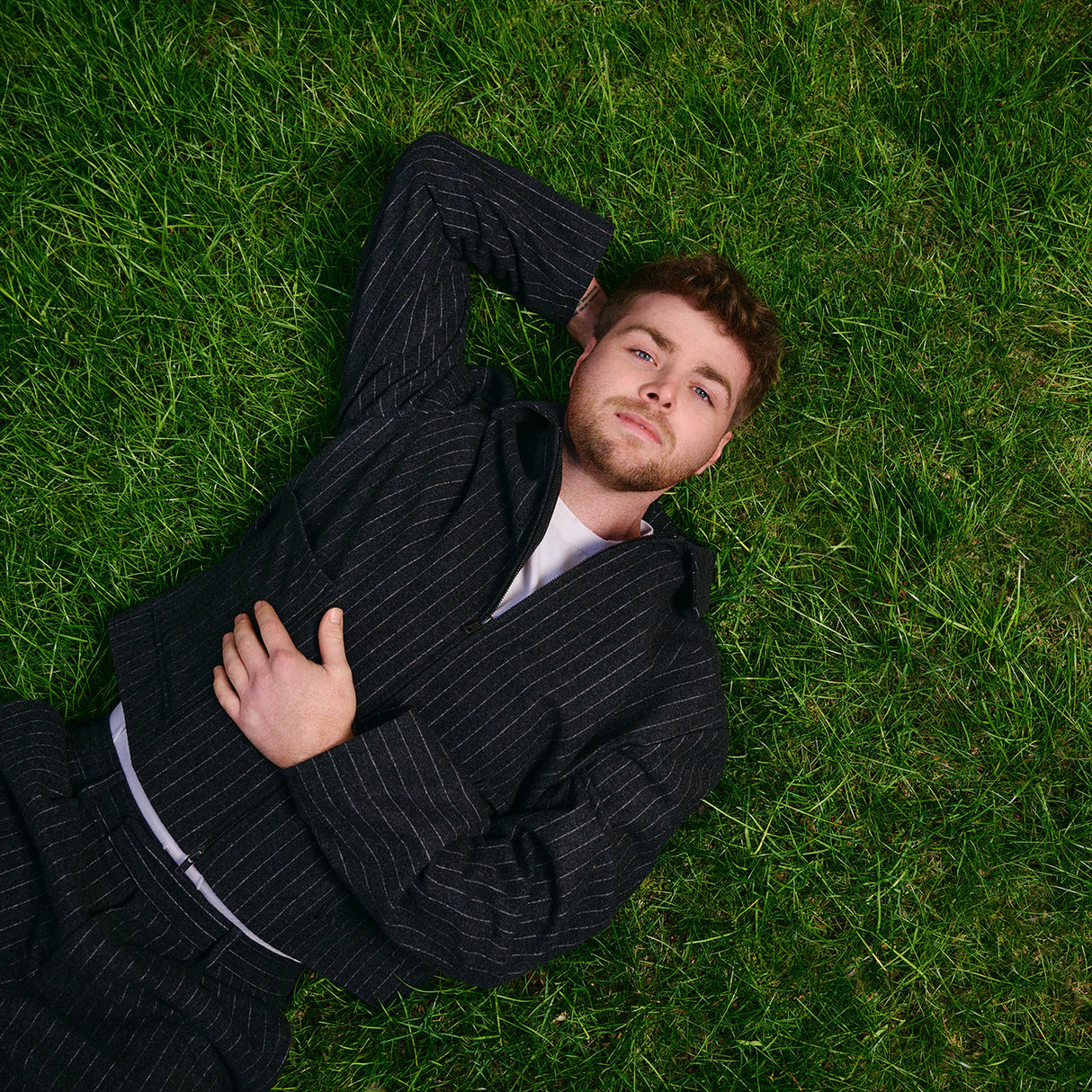 Man in a suit lying on grass