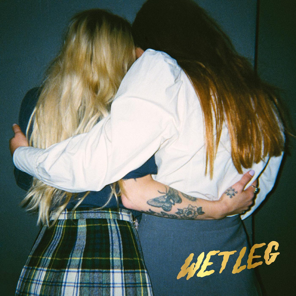 Two people hugging with 'WET LEG' text on a dark background