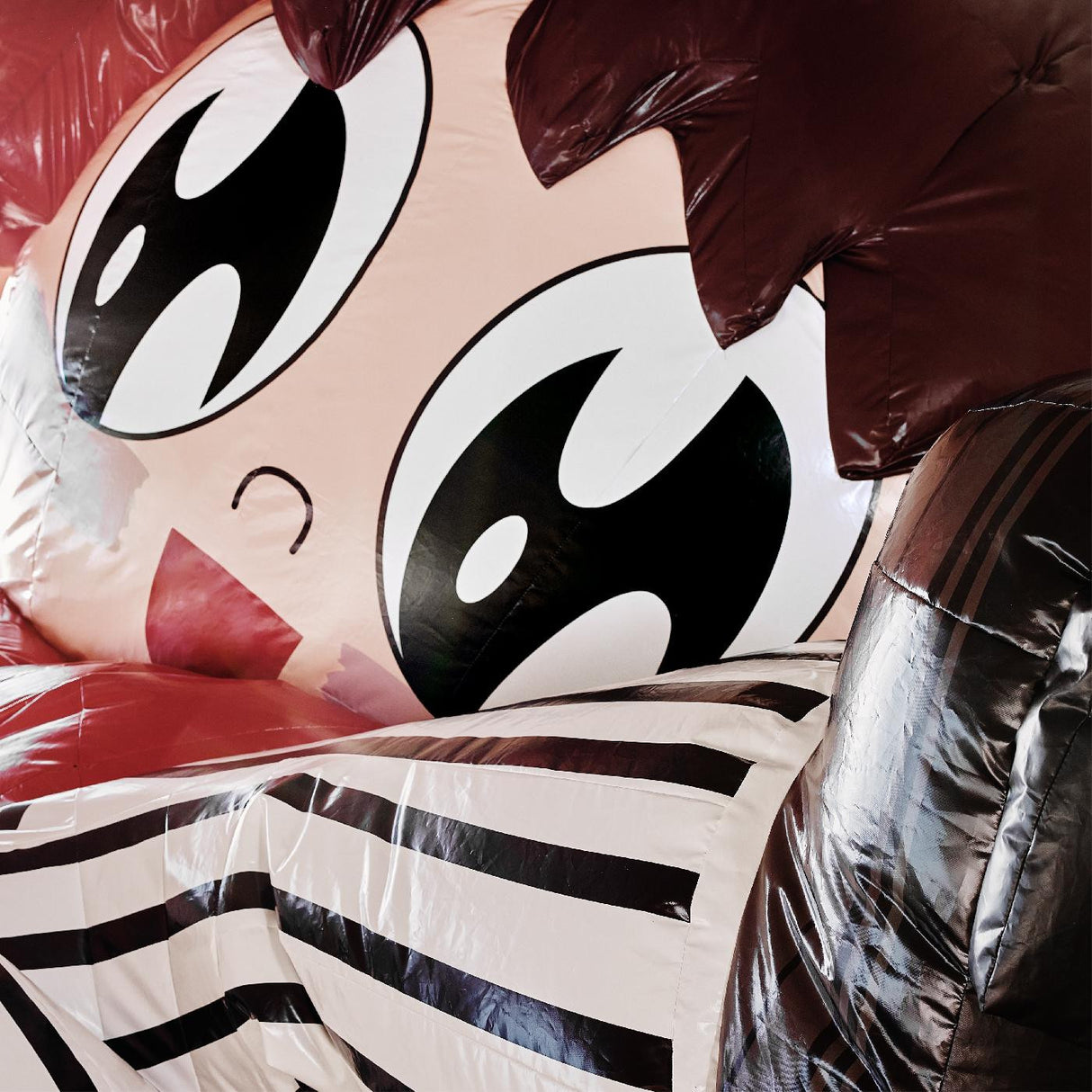 A close-up of a colorful vinyl record with a cartoonish character design, predominantly featuring eyes and hearts, in a striped background.