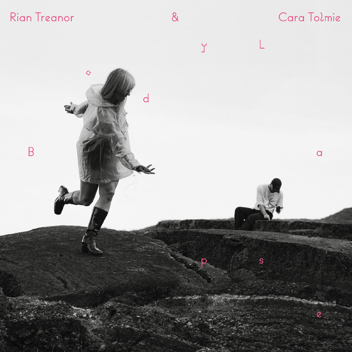Album cover with two people on a rocky landscape, featuring text at the top.
