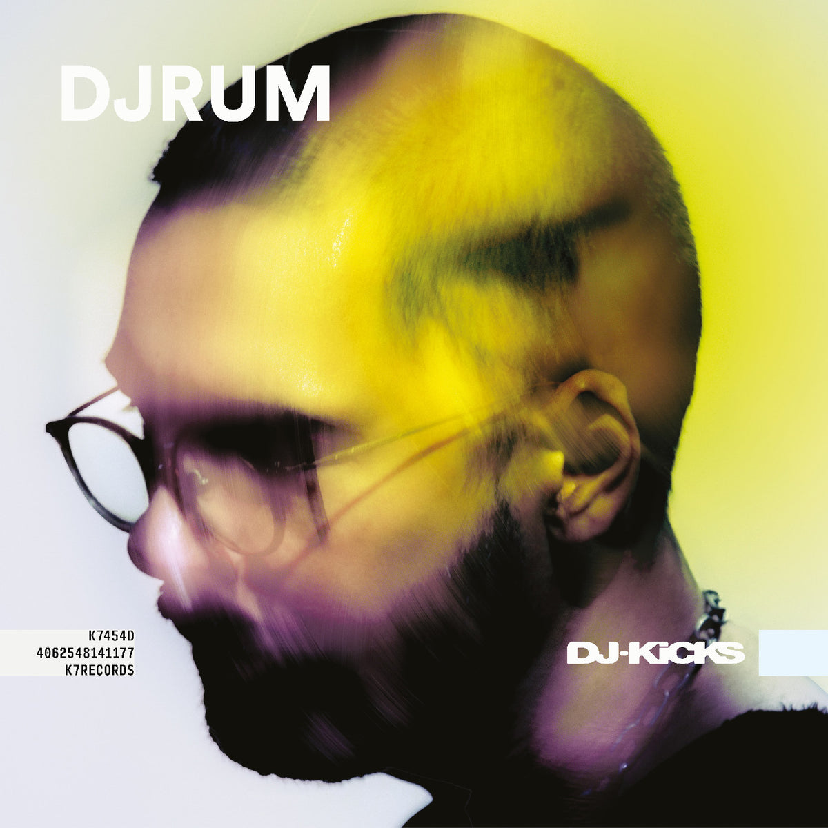 A stylized square cover image featuring a close-up side profile of a bearded man wearing glasses, overlaid with a yellow and purple translucent face wash or reflection effect. Large white text at the top reads DJRUM, and smaller text at the bottom left includes track codes; DJKICKS branding appears at the lower right.