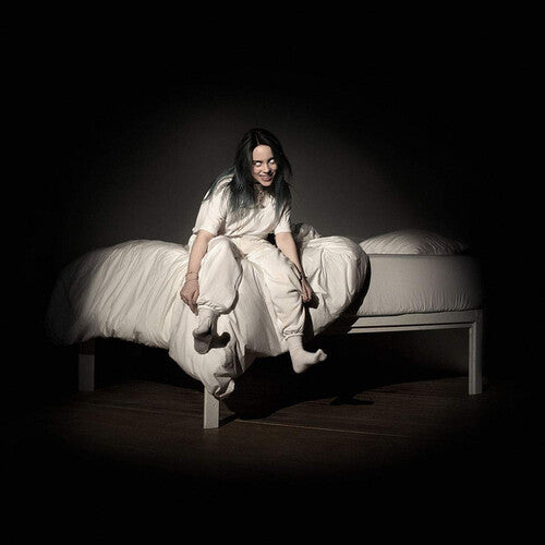 Person sitting on a bed in a dark room, wearing a white dress.