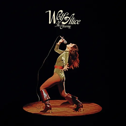 Album cover for 'The Warning' by Wolf Alice featuring a person in a green outfit with a microphone.