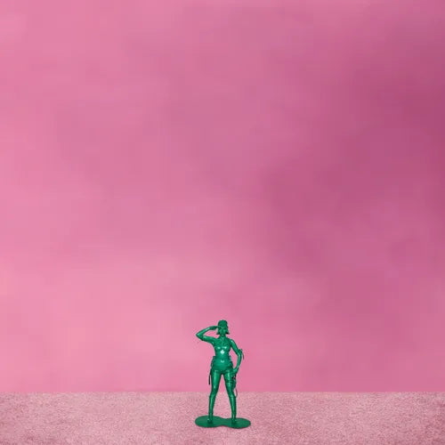 Green toy soldier figure on a pink background