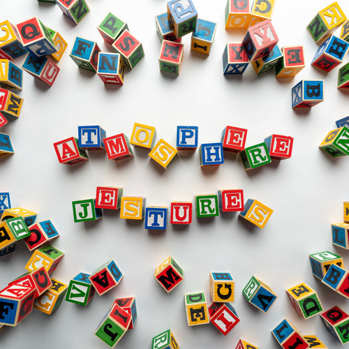 Colorful alphabet blocks spelling out 'ATMOSPHERE JESTURES' on a white background