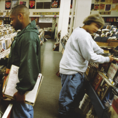 Two people browsing through records in a store, with a variety of vinyl records visible in the background.