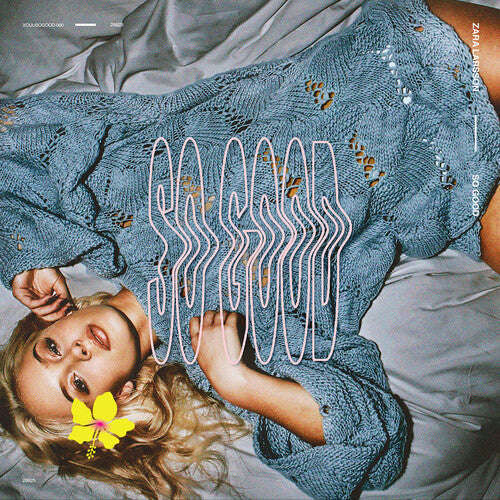 Person wearing a blue knitted sweater with decorative elements on a bed
