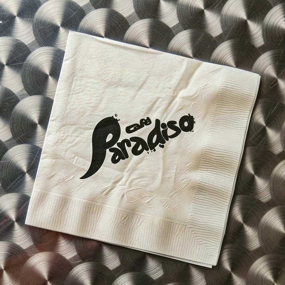 Beige napkin with 'Cafe Paradiso' text on a textured surface