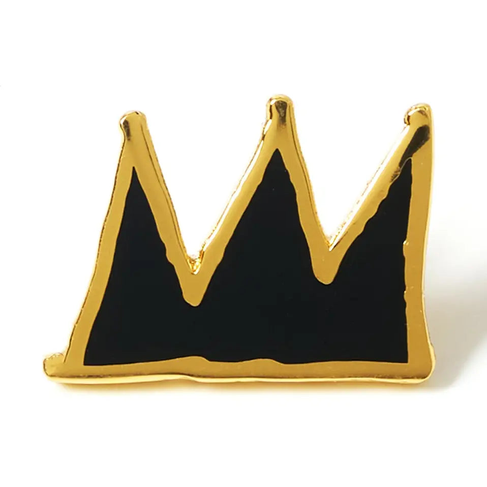 A small crown-shaped enamel pin with a gold metal outline and black enamel fill, photographed on a plain white background.