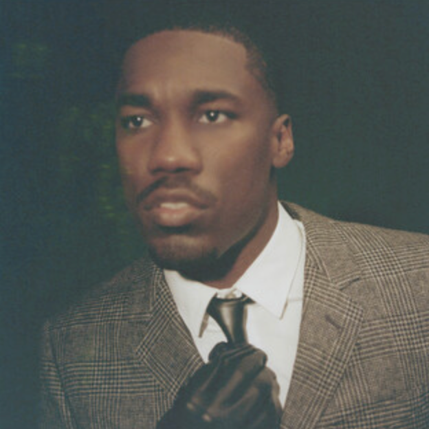 Man in a suit holding a gun against a dark background
