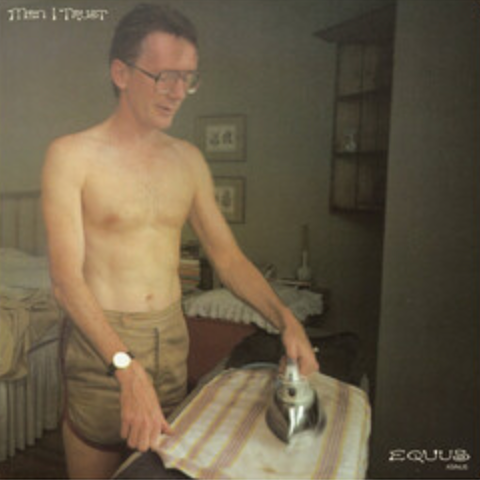 Man ironing clothes in a room with visible 'EQUUS' branding.