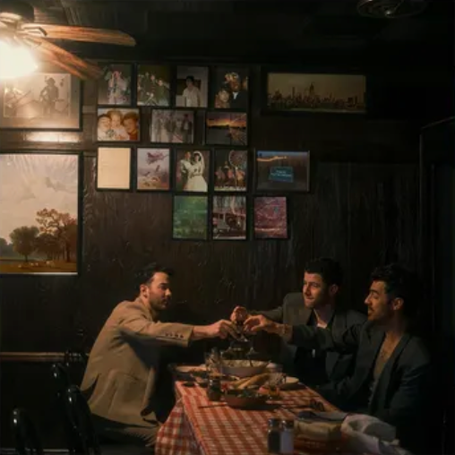 Three men sitting at a table in a dimly lit room with framed pictures on the wall.