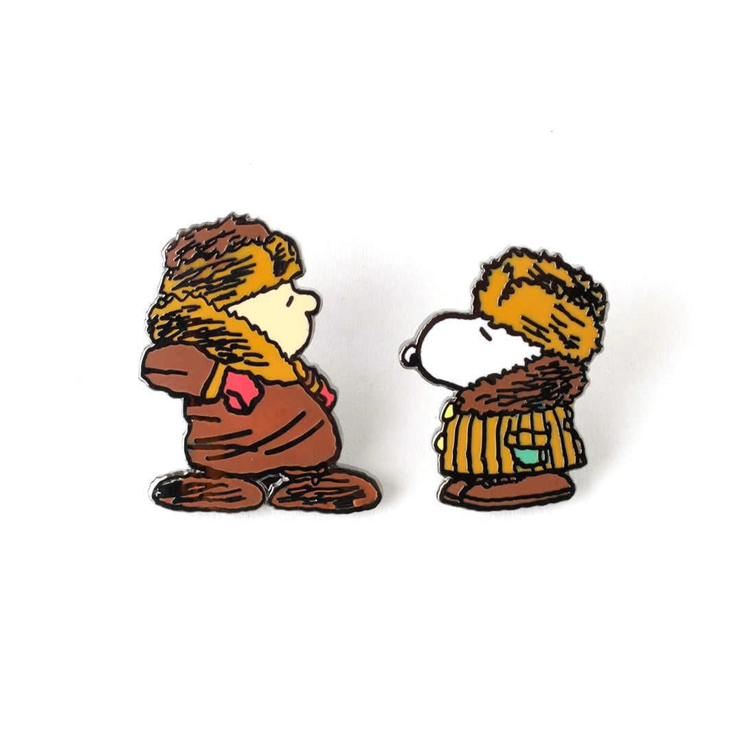 Two Snoopy and Woodstock enamel pins on a white background, one showing Woodstock in a brown outfit and the other showing Snoopy in a yellow striped sweater.