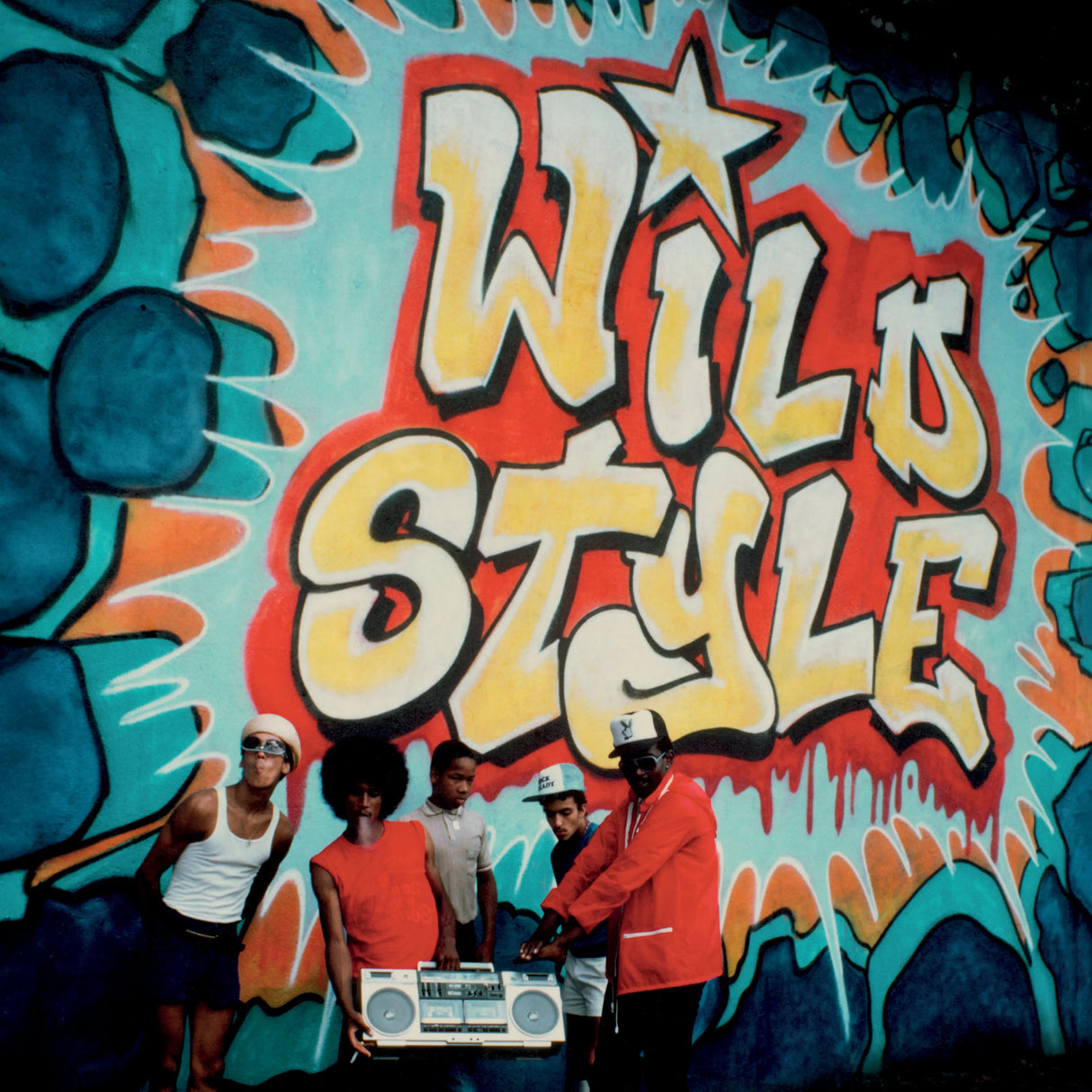 Group of people posing in front of a colorful mural with 'Wild Style' text