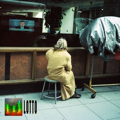 Person sitting on a stool in front of a television screen displaying a man in a suit.