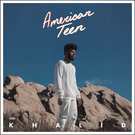 Cover art for Khalid's album 'American Teen' featuring the artist in a white outfit standing against a backdrop of a clear sky and rocky landscape.