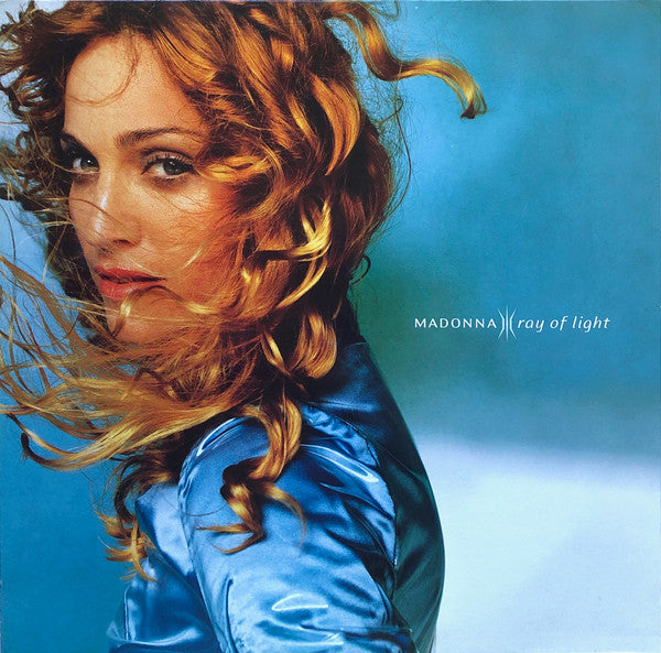 Album cover of 'Ray Of Light' by Madonna featuring a photo of the artist with red hair, wearing a blue satin robe against a blue background.