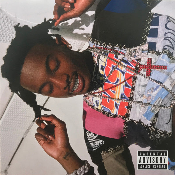 This image features the album cover for "Playboi Carti – Playboi Carti LP," showcasing the artist, Playboi Carti, in a relaxed pose against a vividly patterned backdrop. The cover art includes a "Parental Advisory" label, indicating explicit content.