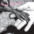 This image features the album cover of the Dead Kennedys' LP, "Plastic Surgery Disasters." It displays a haunting and evocative photograph of a pair of hands, one healthy and the other withered, set against a dark, textured background.