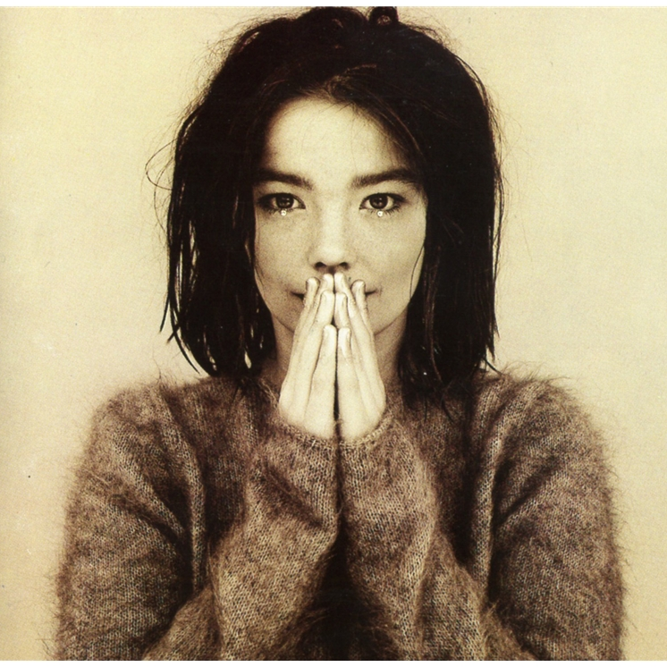 A vinyl record album cover featuring a young woman with her hands pressed together in front of her face. She is wearing a brown, textured top and the background is plain.