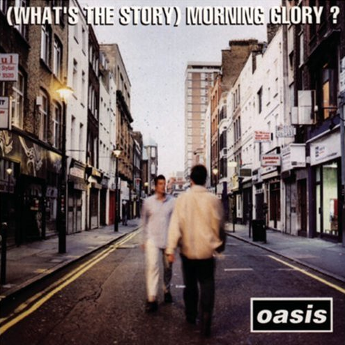 The album cover of Oasis' '(What's The Story) Morning Glory?' featuring a blurred photograph of a city street leading to a record store, with the band's logo at the bottom.