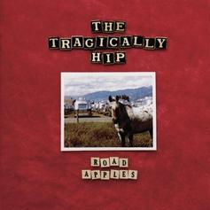 The album cover of 'The Tragically Hip - Road Apples LP' featuring a red background with a picture of a cow in the center.