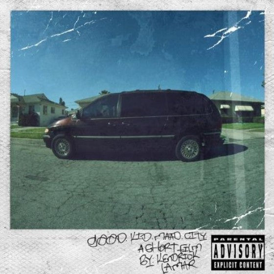 A vinyl record album cover featuring a dark-colored minivan parked on a street with houses in the background. The sky is clear and it appears to be a sunny day.