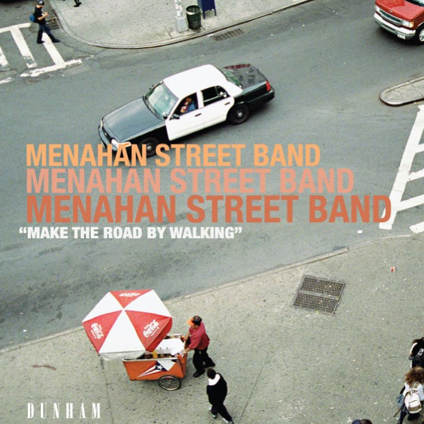Album cover for Menahan Street Band featuring a city street scene with a red umbrella, people walking, and a car in the background.