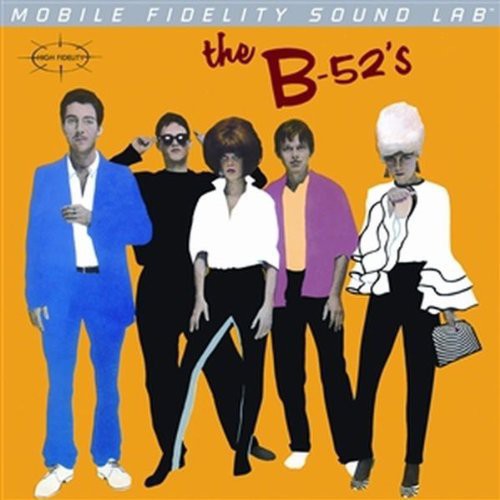 Album cover of 'The B-52's' with five band members in colorful outfits on an orange background.