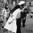 Black and white photograph of a sailor and nurse embracing on a city street.