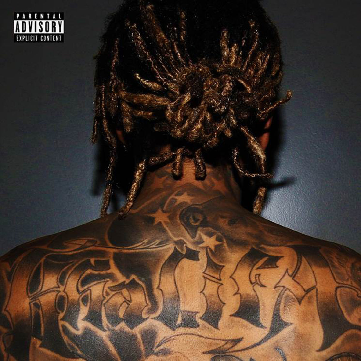 Person with intricate tattoos on their back against a dark background
