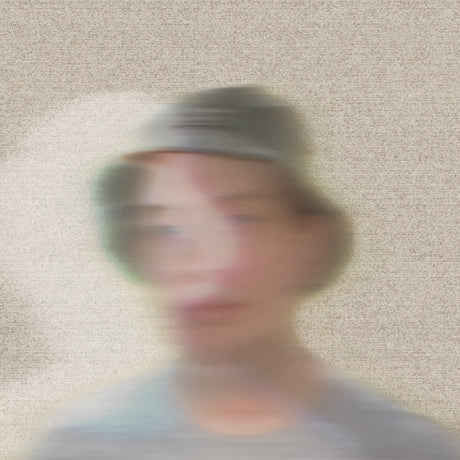 Blurred image of a person wearing a cap against a textured beige wall.