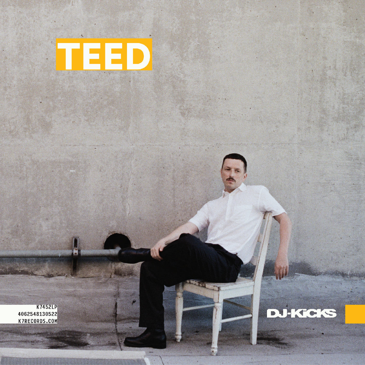Man sitting on a chair against a concrete wall with 'TEED' branding.