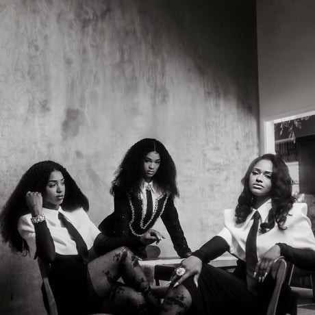 Black and white photo of three women sitting together in a room with a textured wall.