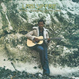 Album cover featuring a person with a guitar sitting on rocks by the water, with 'Labi Siffre' and album title text.