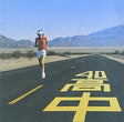 Person running on a desert road with mountains in the background