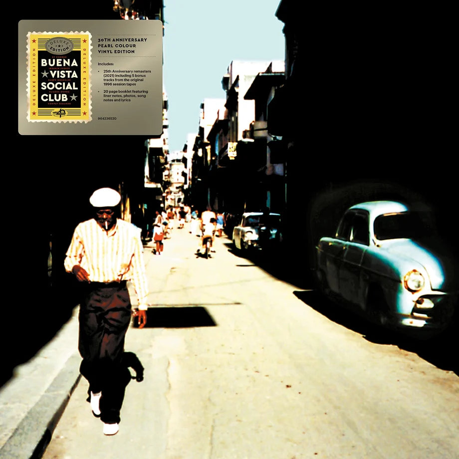Album cover art for Buena Vista Social Club's 20th Anniversary World Tour, featuring a man walking down a sunlit street with vintage cars on the right, with a vinyl record sleeve graphic overlaid in the top-left corner.