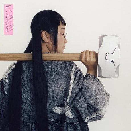 A person with a hot pink vinyl record labeled 'Yaeji - With A Hammer' placed against their head, featuring a marker drawing.