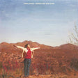 Album cover with a person standing in a desert landscape with mountains in the background.