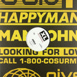 A white vinyl record with a black and white XL Records label sits centered on a black background printed with bold yellow text.