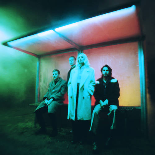Four people sitting inside a colorful, abstract light box.