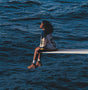 Person sitting on a diving board over a body of water