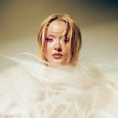 Person with blonde hair and red eyes surrounded by white fluffy material on a beige background