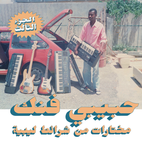 Person holding a keyboard with musical instruments and a car in the background