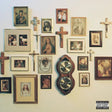 Wall with framed pictures, crosses, and a clock, featuring a 'Parental Advisory' label.