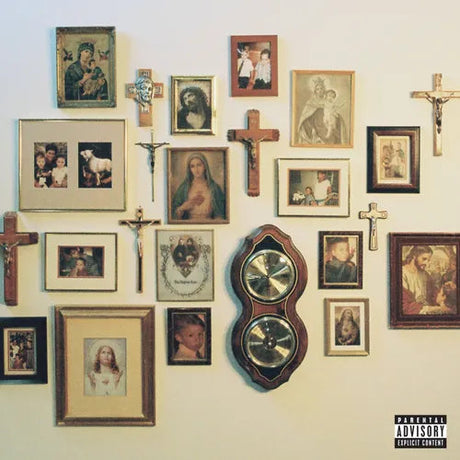 Wall with framed pictures, crosses, and a clock, featuring a 'Parental Advisory' label.