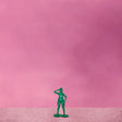 Green toy soldier figure on a pink background