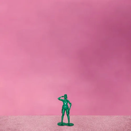 Green toy soldier figure on a pink background