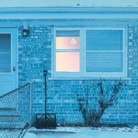 Brick house with a window showing a pink sky, snow on the ground, and a shovel outside.